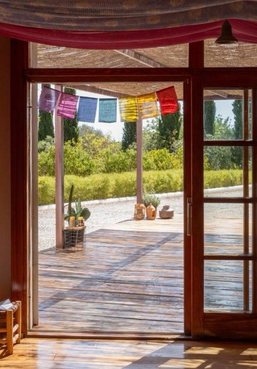 Yoga retreat voor vrouwen, open deuren naar terras met uitzicht op natuur en kleurrijke vlaggen